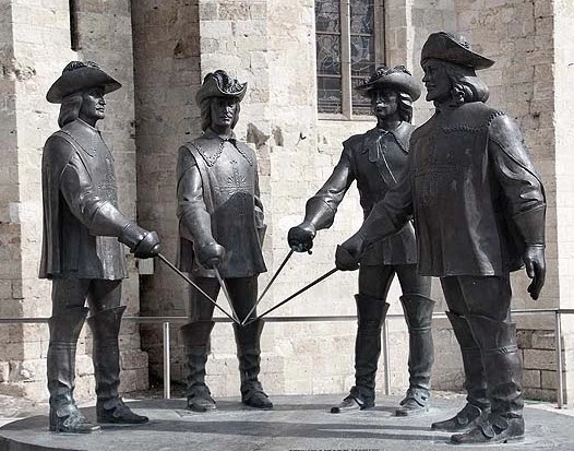 Quatre statues de bronze représentant les Mousquetaires (d'Artagnan, Porthos, Aramis et Athos)